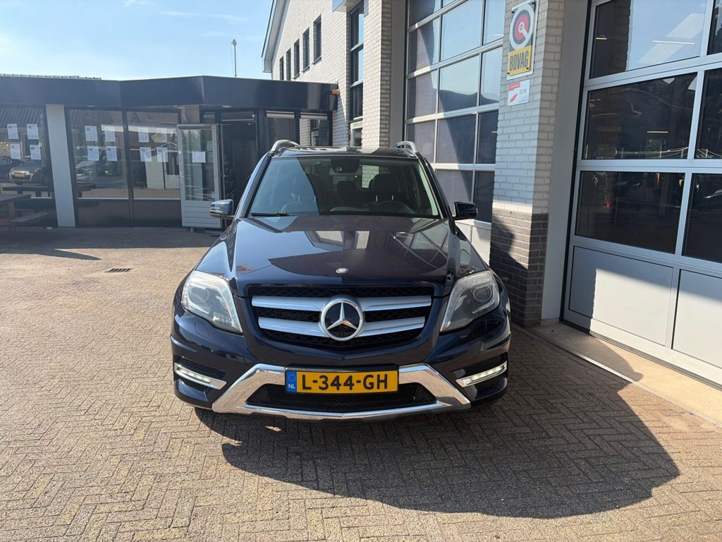 Het pand van Autobedrijf Van Oostrum aan de Heeswijk met de ingang van het kantoor en de werkplaatsdeuren