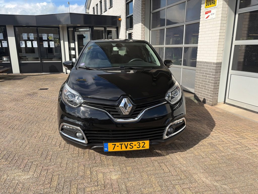 Zwarte Renault Captur op het terrein van Autobedrijf Van Oostrum, met de ingang van het kantoor en de werkplaatsdeuren