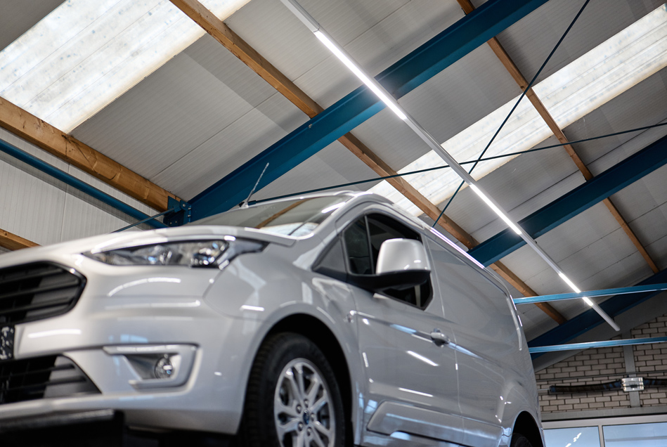 Grijze Ford Transit Connect in de werkplaats, onder de blauwe spanten en de nieuwe lichtlijnen